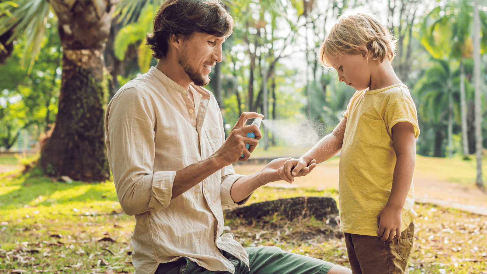 Uncover 11 Must-Have Summer Travel Accessories 11 Dad spraying son with insect repellant