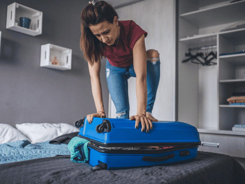 10 Things You MUST Avoid: Never Do These Things on a Cruise 1 Woman forcing overpacked suitcase down