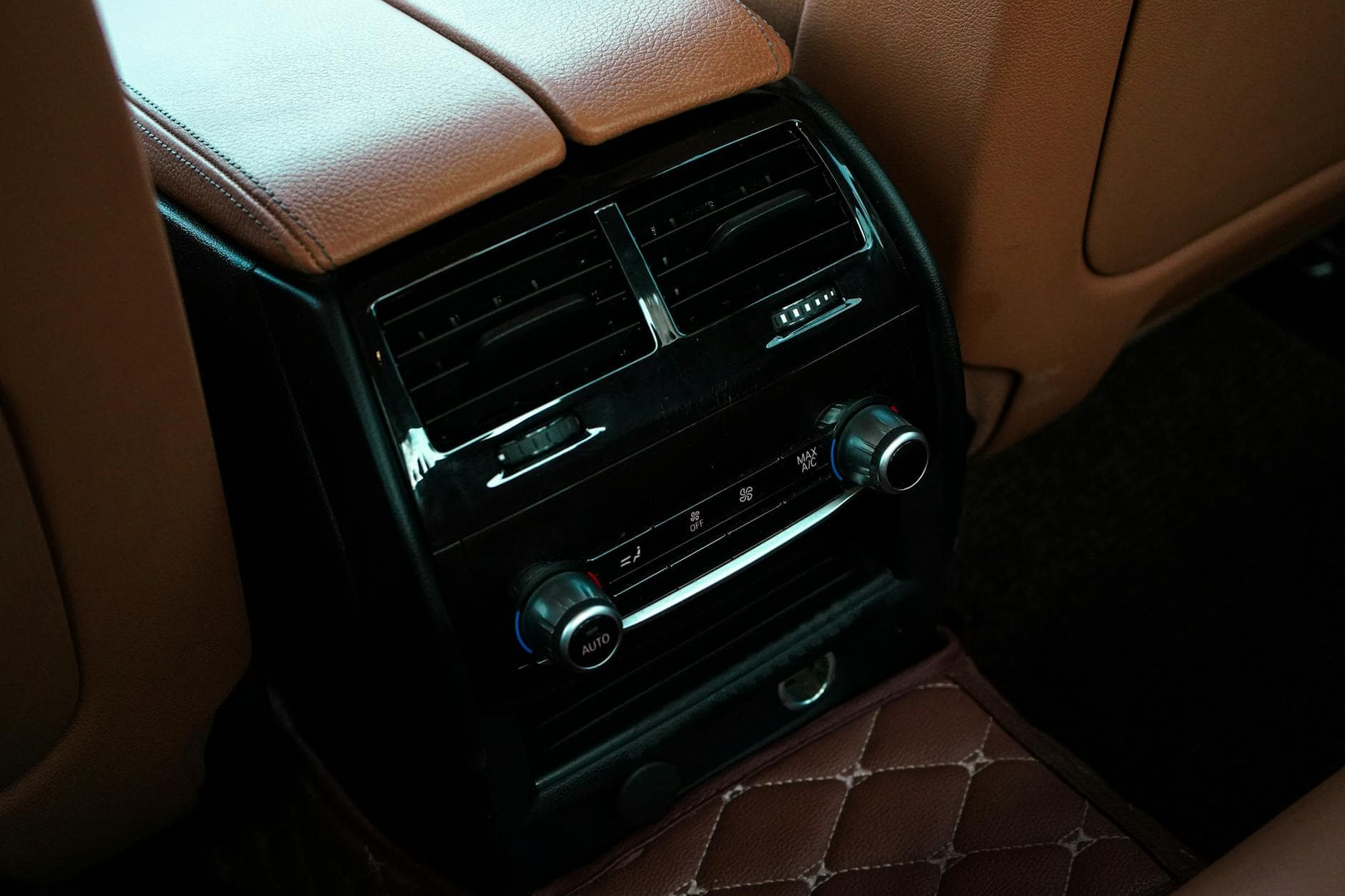 15 Road Trip Car Organizers for Traveling With Kids 7 Close-up of a luxury car interior showcasing leather seats and climate control with air conditioning and radio controls.