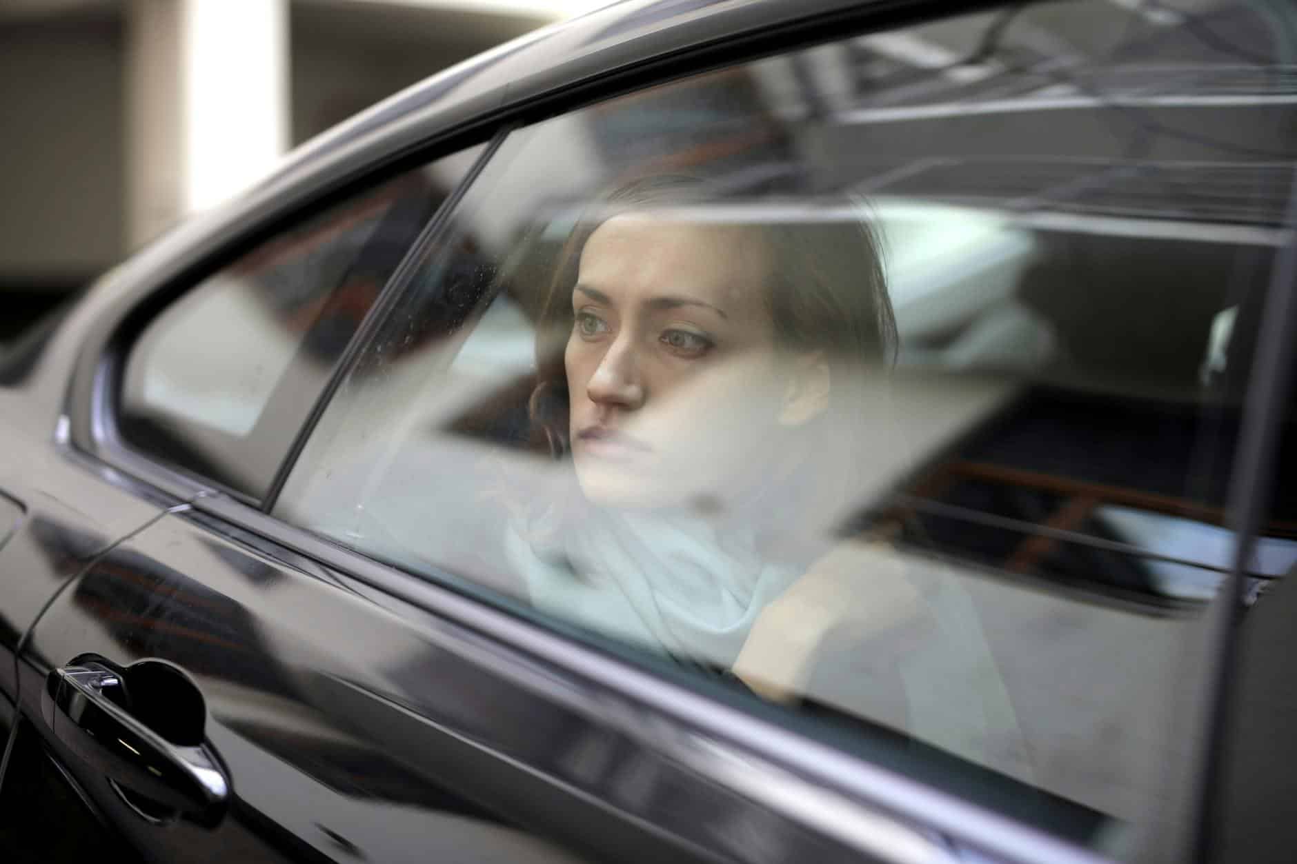 15 Road Trip Car Organizers for Traveling With Kids 8 A thoughtful woman gazes out of a car window, lost in contemplation, conveying deep emotions.