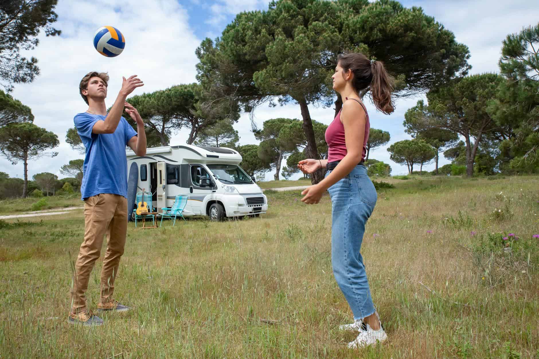 15 Road Trip Car Organizers for Traveling With Kids 15 A young couple plays volleyball near their camper van in a scenic outdoor setting in Portugal.