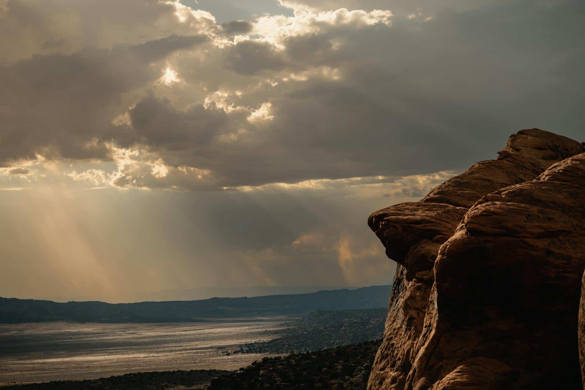 Scenic view of Utah's desert landscape with dramatic sunrays and rock formations at sunset.