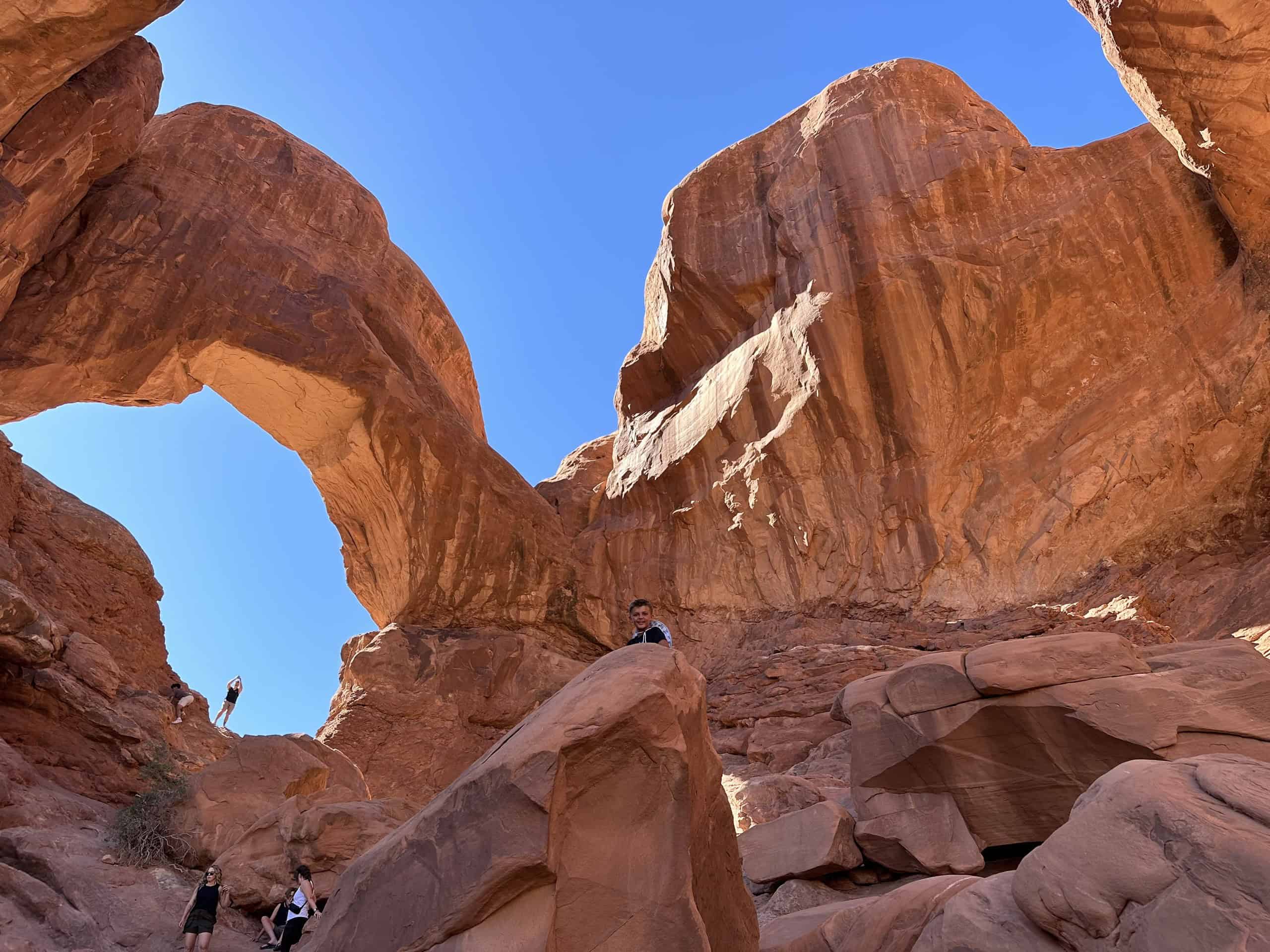We’ve Been to Arches Five Times — Here’s Why We Never Get Tired of It 1 Double Arch in Arches National Park with one of our sons on the boulder below