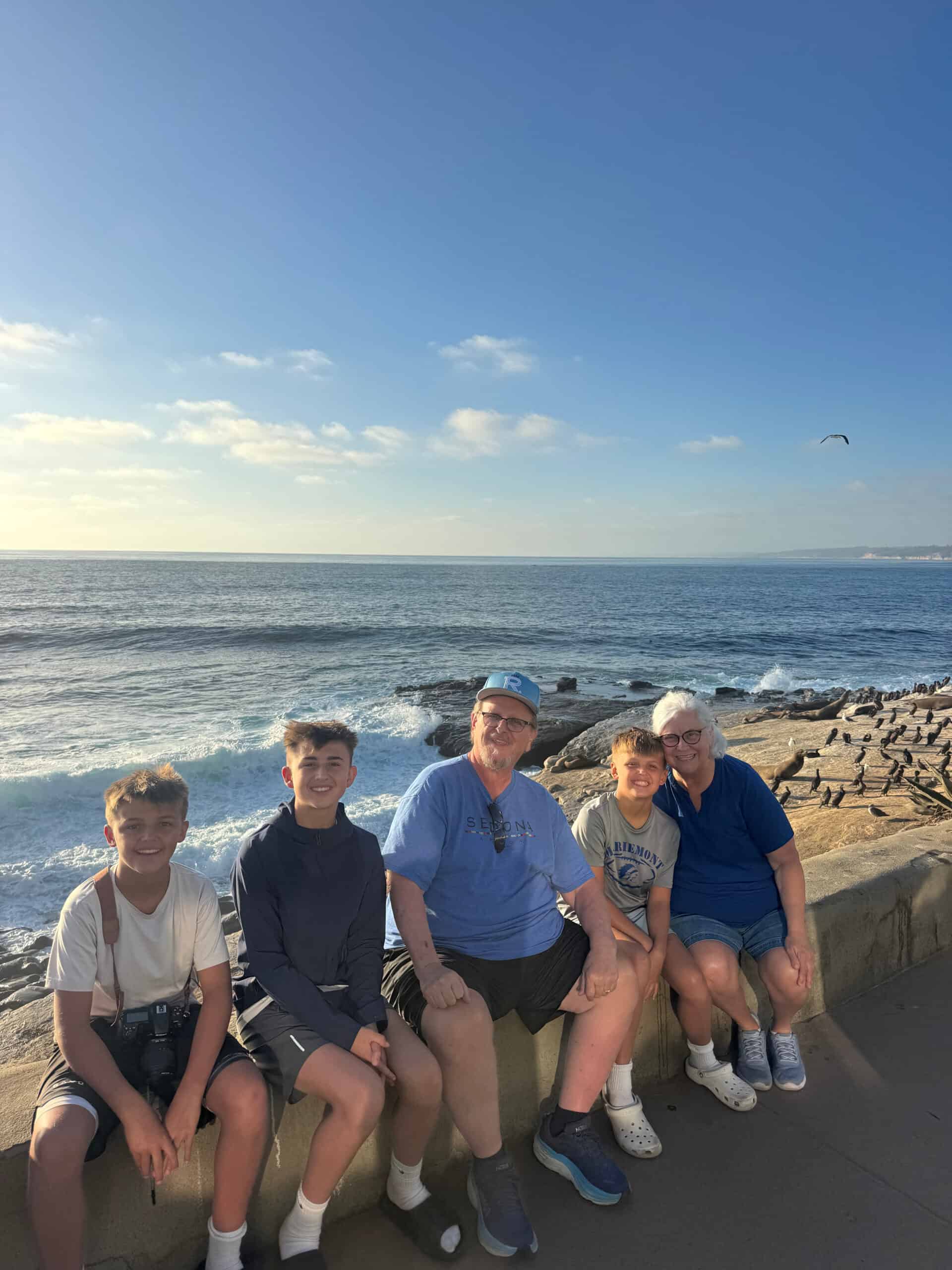 Five travelers sitting together beside the ocean