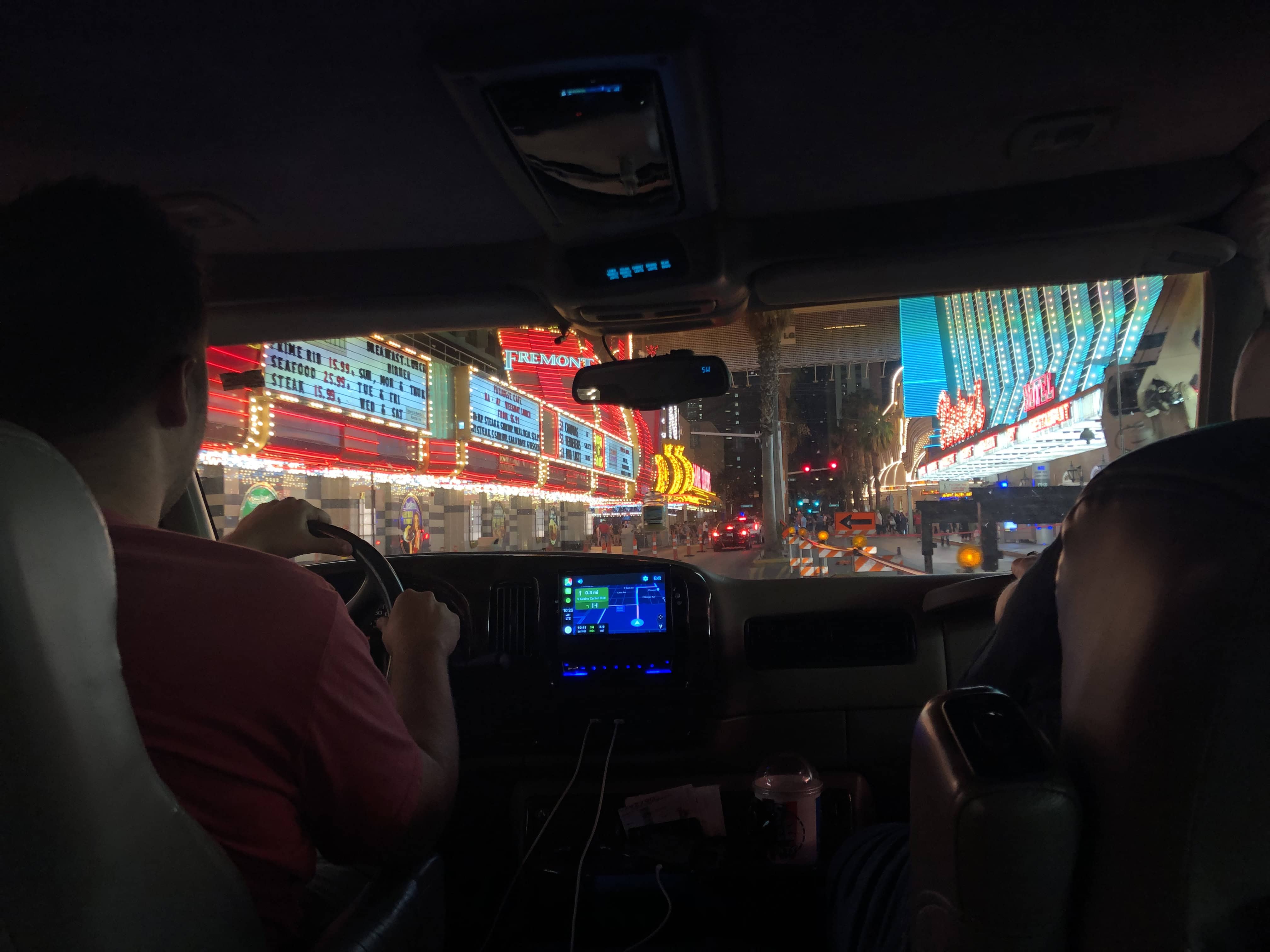 Interior of car at night, view of brightly lit city streets and buildings.