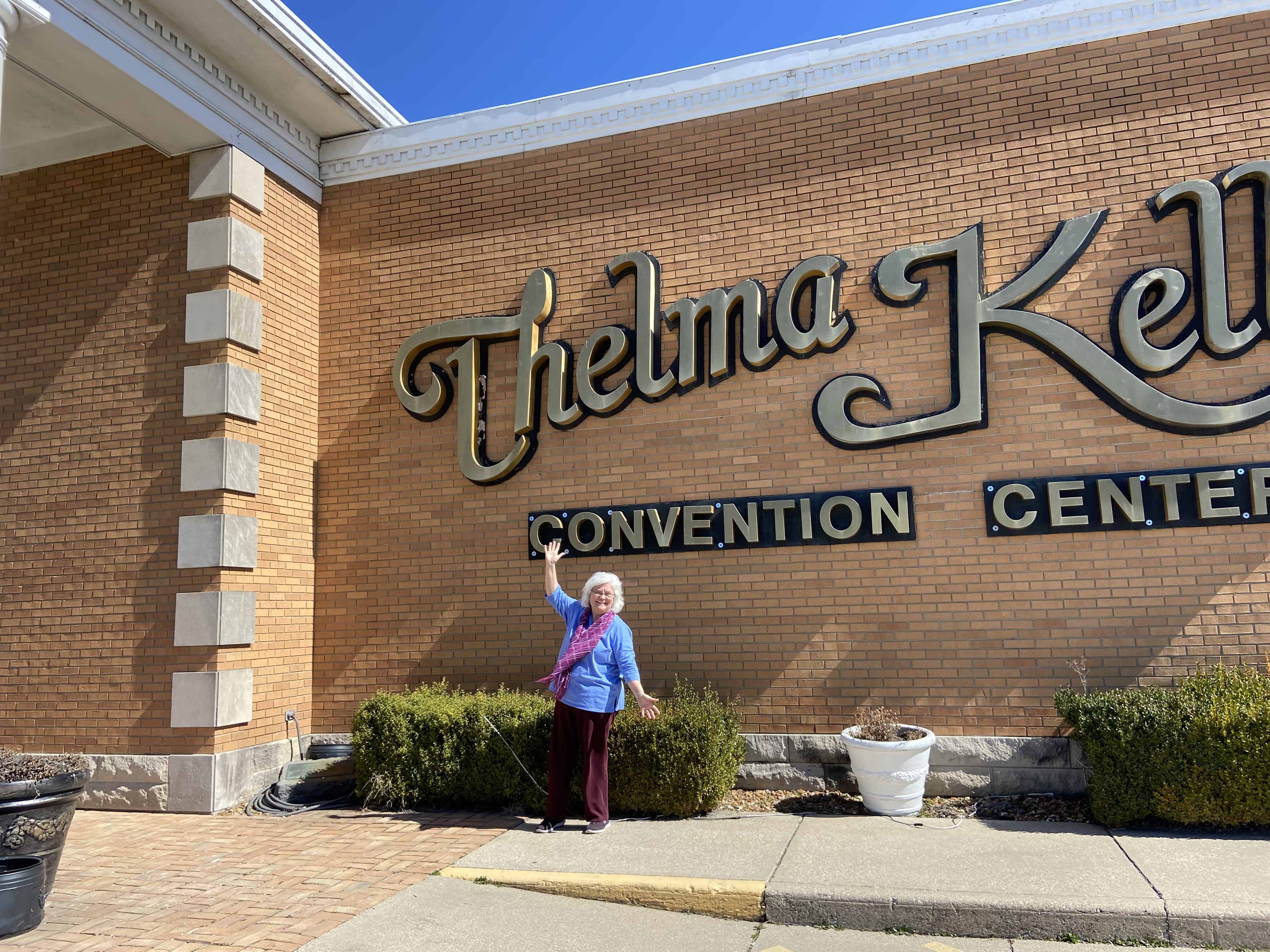 A person posing beside a building on a sunny day.